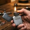 Classic brushed metal Zippo lighter open with flame